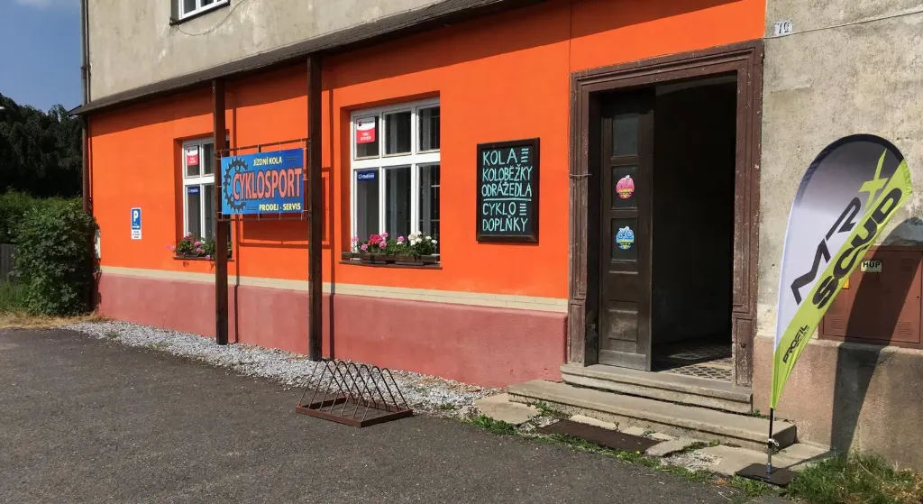 Prodejna CYKLOSPORT – oranžový dům s modrou cedulí na ulici 9. května v Rudě nad Moravou